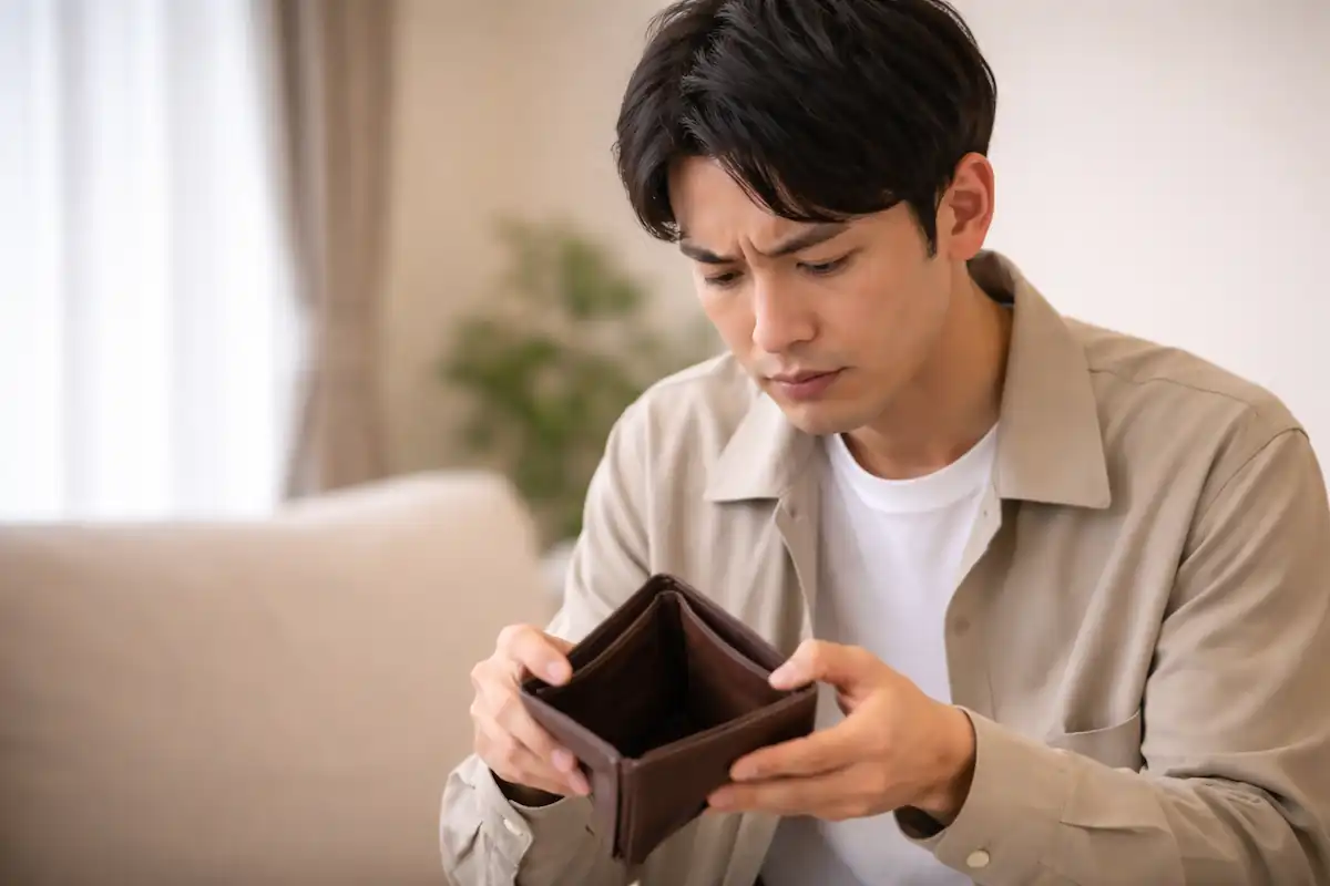 一名日本男性打開錢包查看，發現錢包裡沒有現金，呈現日本生活費壓力的情境